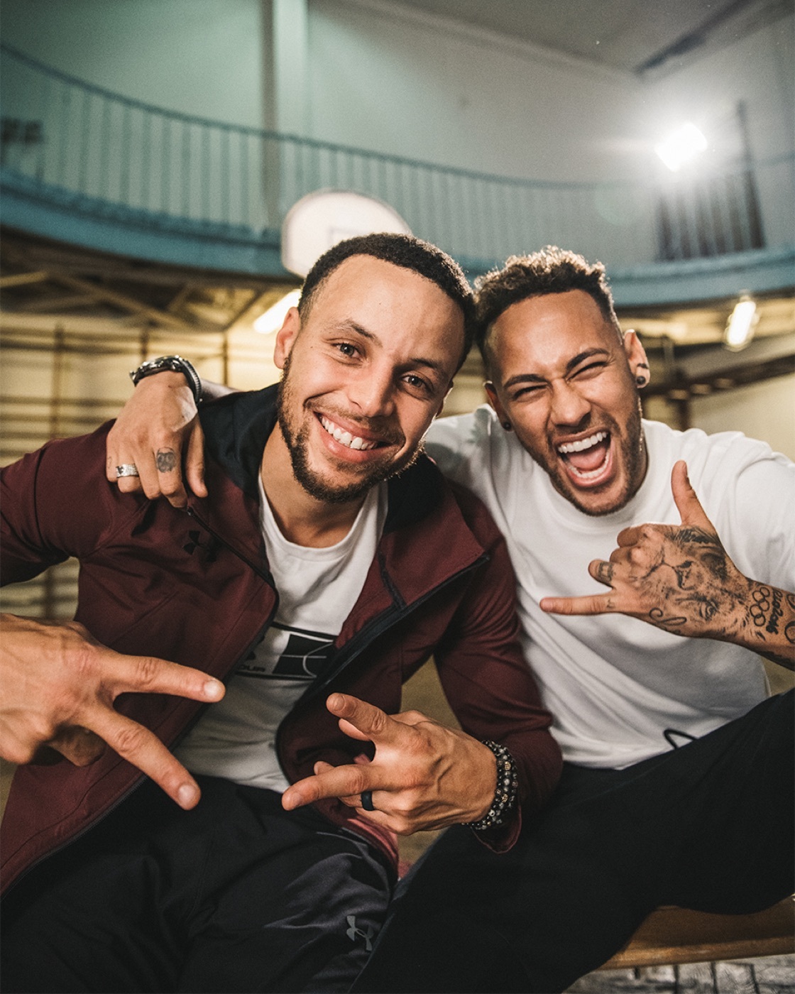 Stephen Curry and Neymar smiling together in a basketball gym