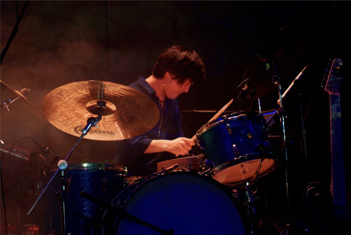 Mir Hwang performing behind a blue sparkle drum kit