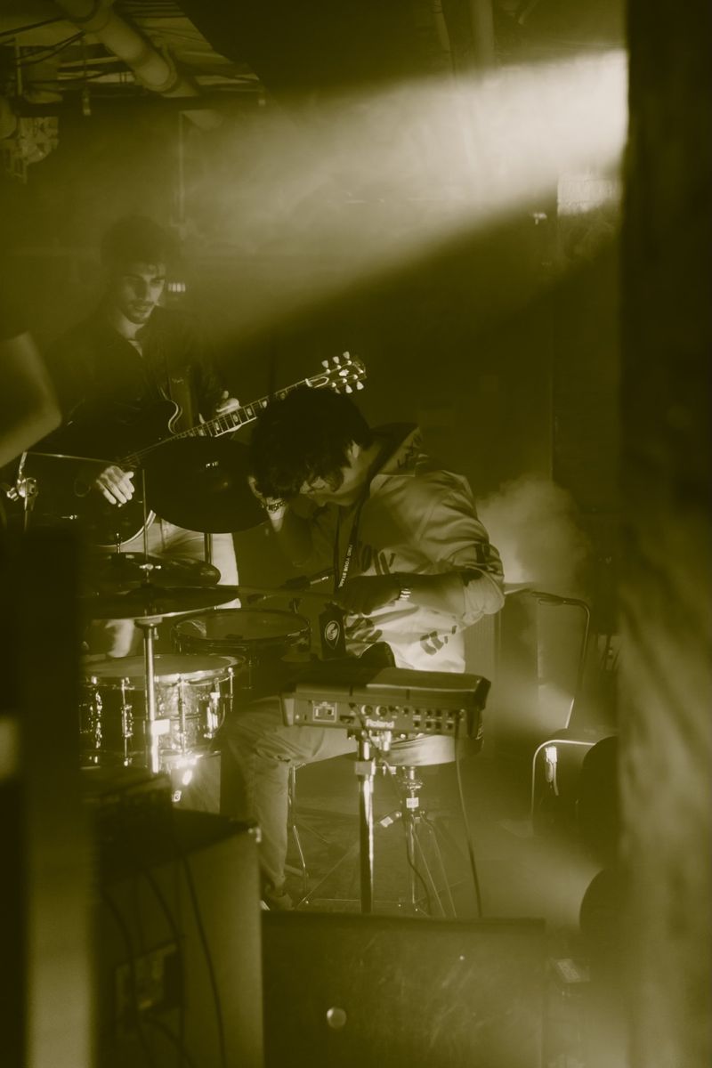 Mir Hwang playing drums on a dimly lit club stage