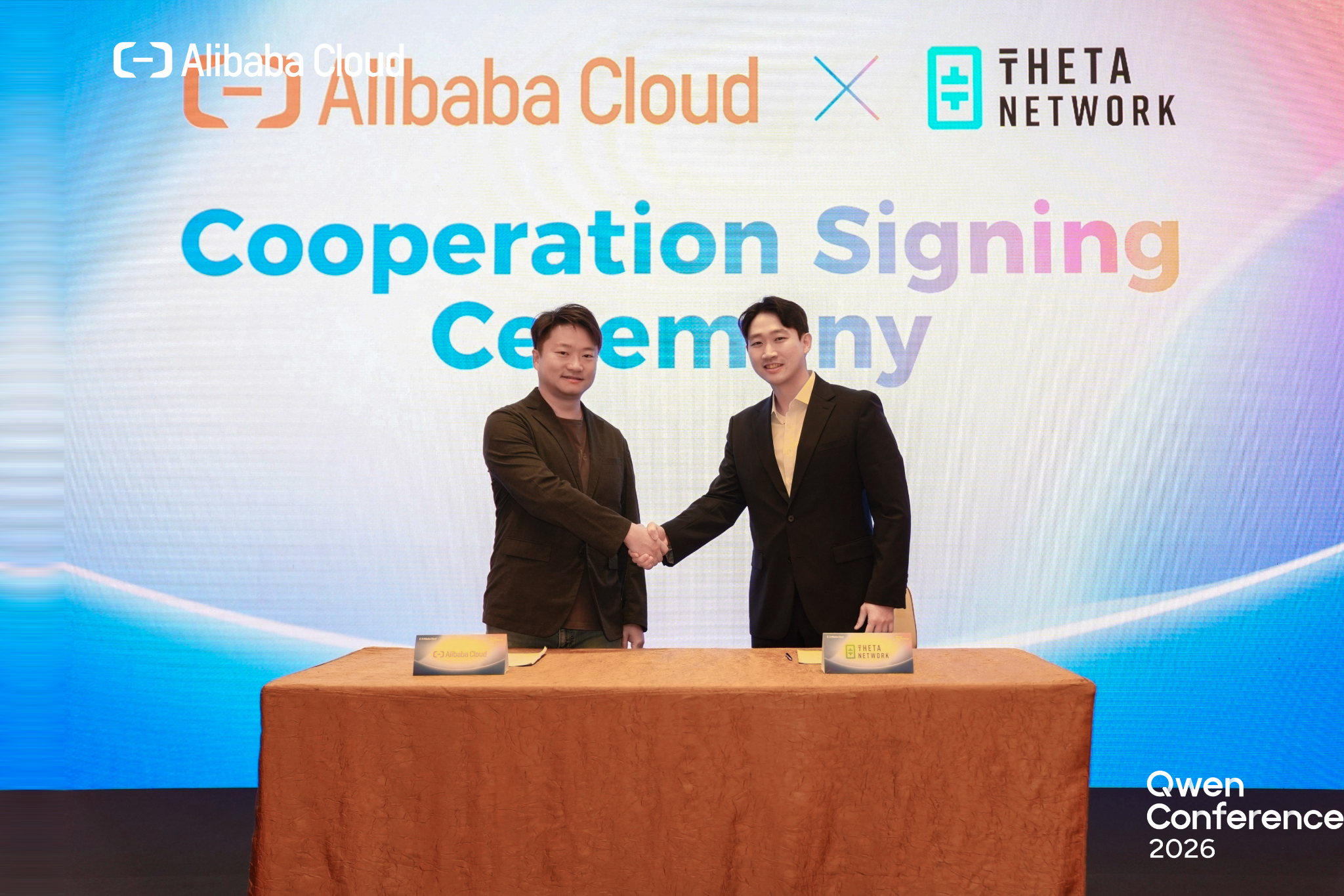 Alibaba Cloud and Theta Network representatives shake hands at the Qwen Conference 2026 cooperation signing ceremony