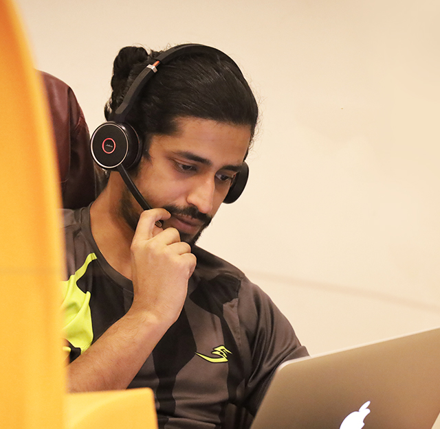 A staff member wearing a headset and working at a laptop in a Mitsogo workplace photograph