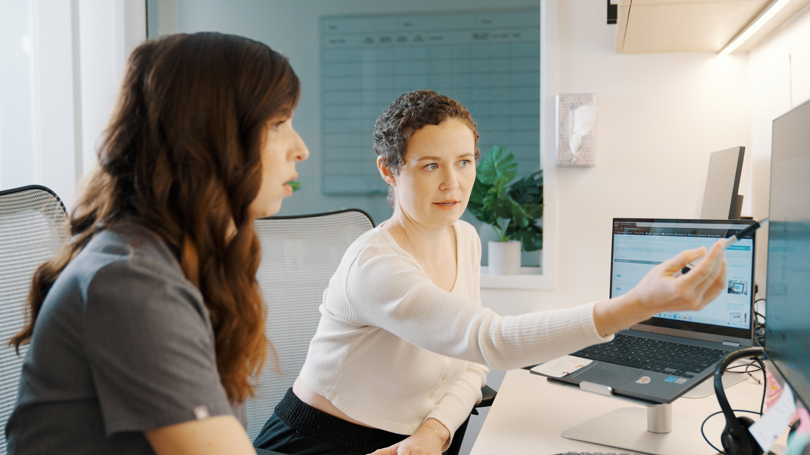 Two Modern Animal team members discussing clinical software at a workstation