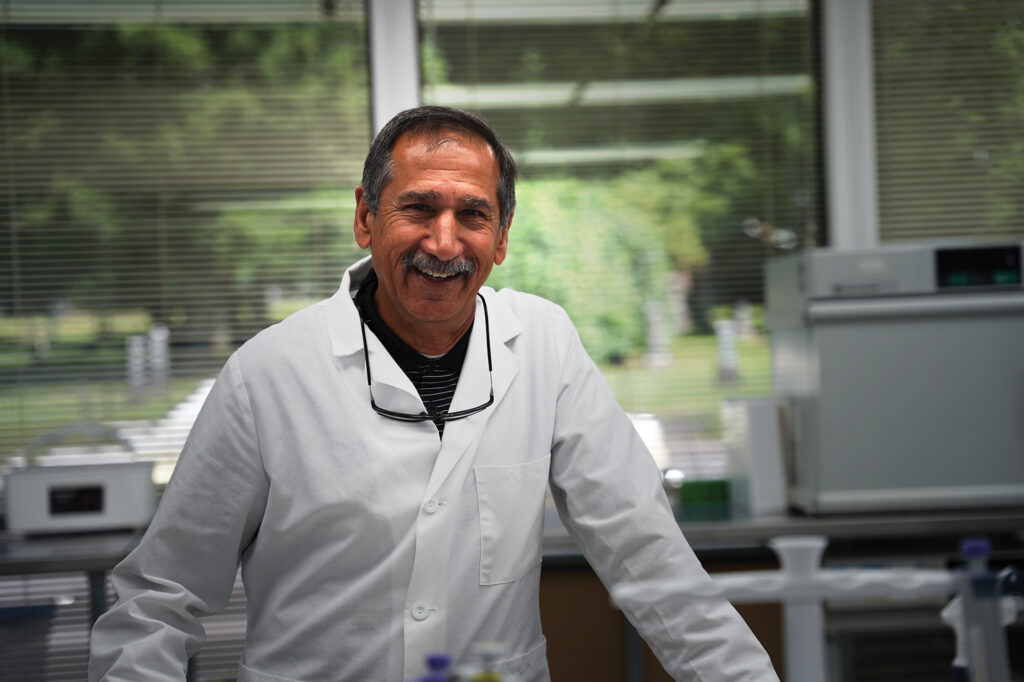 Mohammad Koohmaraie smiling in a white laboratory coat inside a laboratory