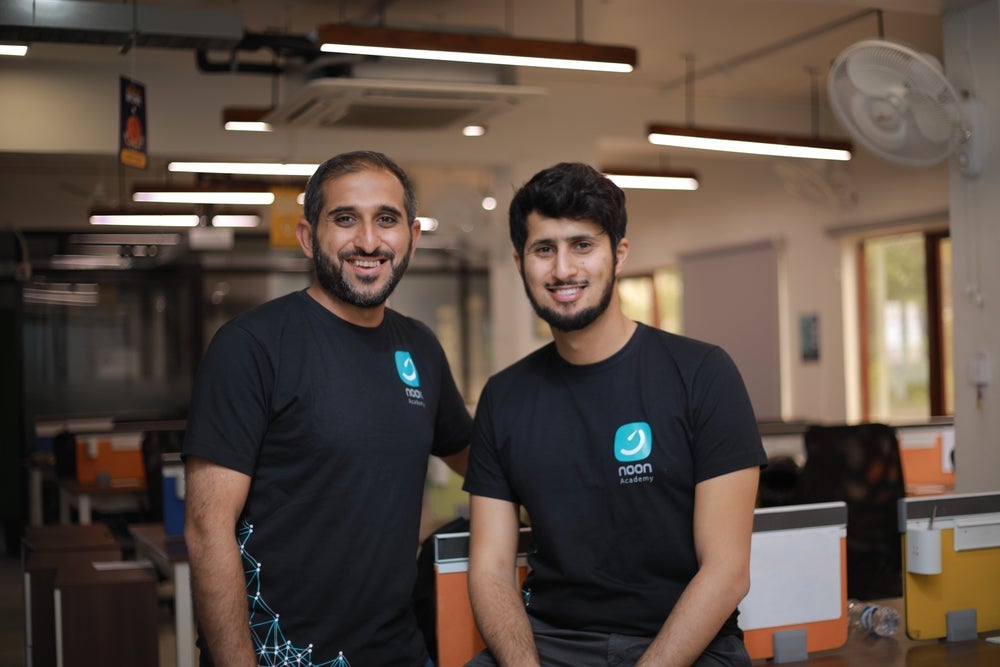 Noon co-founders Abdulaziz AlSaeed, left, and Mohammed Aldhalaan, right, wearing Noon Academy T-shirts in an office