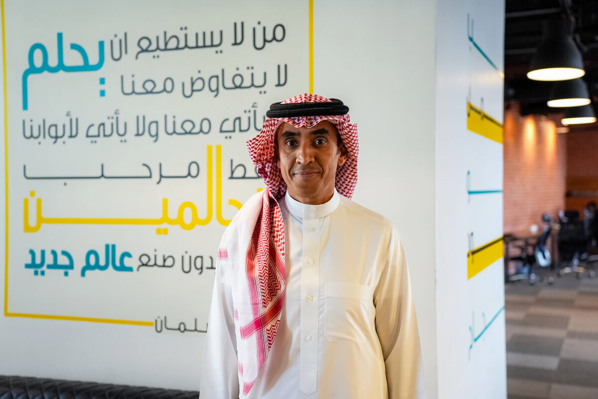 Mohammed Alhussein at Mozn’s Riyadh office, standing beside a wall of Arabic lettering