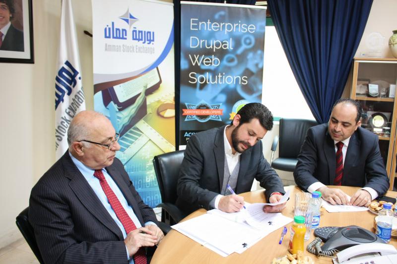 Mohammed Razem signs the Amman Stock Exchange website agreement at a conference table in 2018