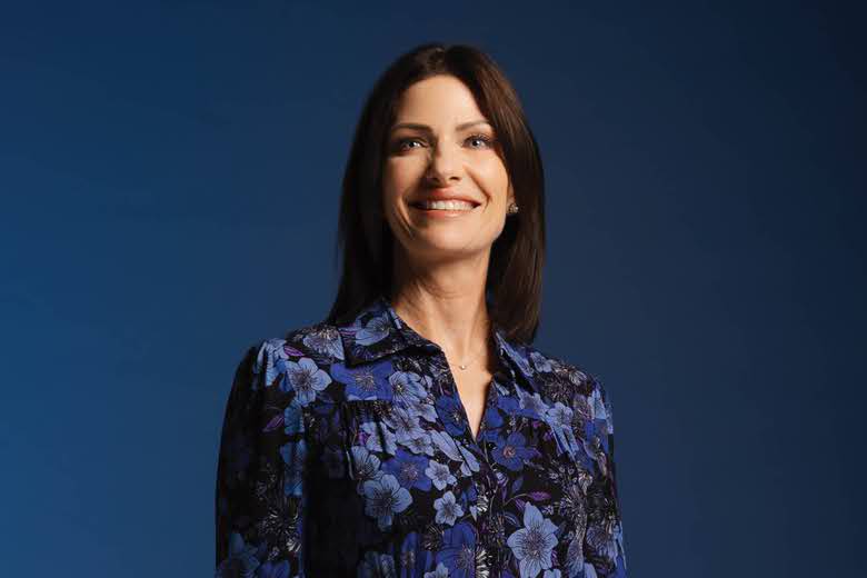 Molly Hamrick in a floral blouse against a navy background