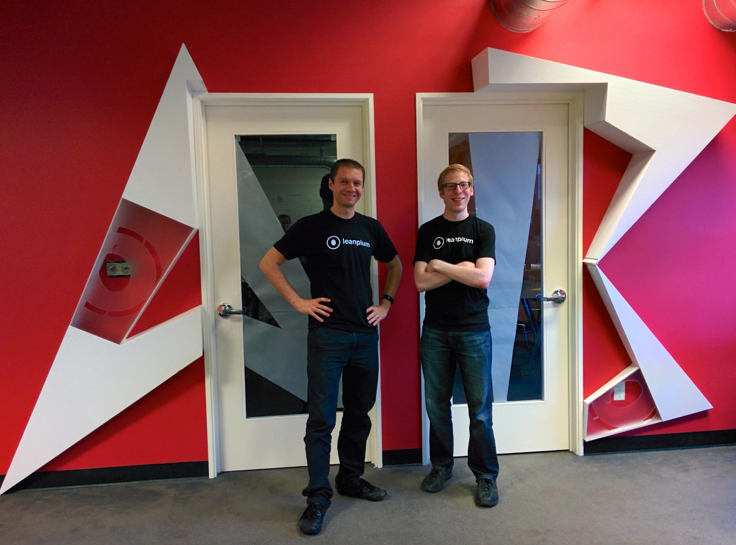 Momchil Kyurkchiev, left, and Andrew First in Leanplum shirts beside the office conference rooms marked A and B.