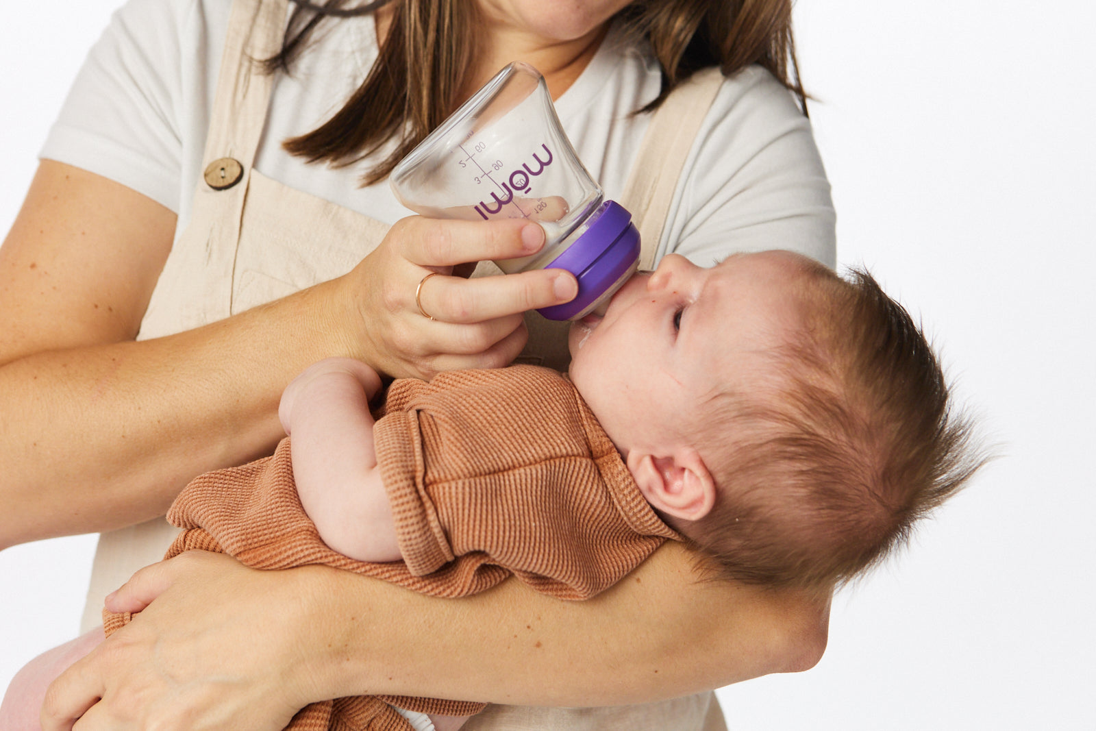 Parent feeding a baby with a mōmi bottle