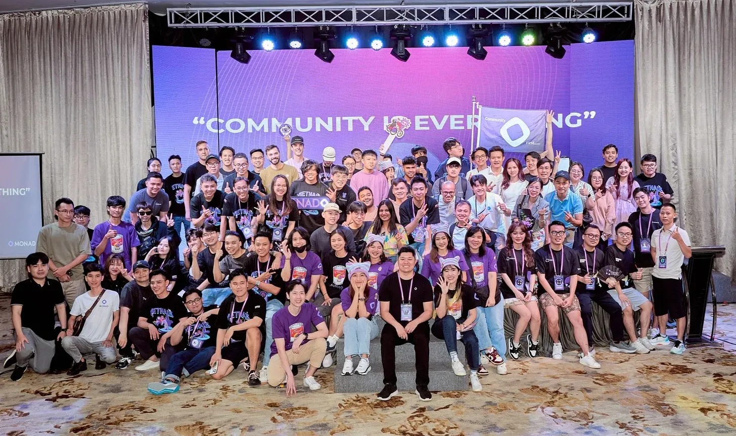 Monad community members gathered on a purple-lit stage at a Vietnam meetup