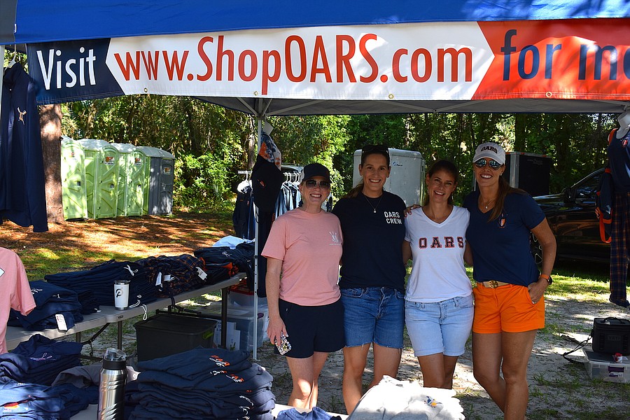 Four Orlando Area Rowing Society volunteers, including Monica Kozak, at a merchandise table during the 2022 open boathouse