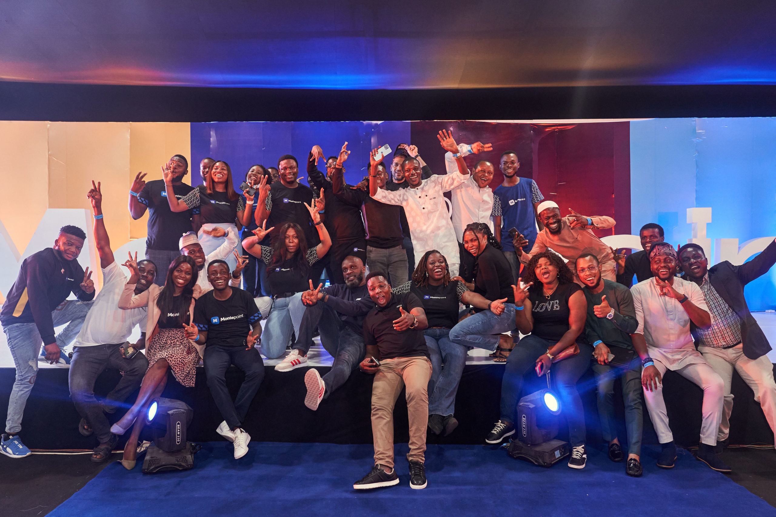 Moniepoint team members posing together on a brightly lit stage
