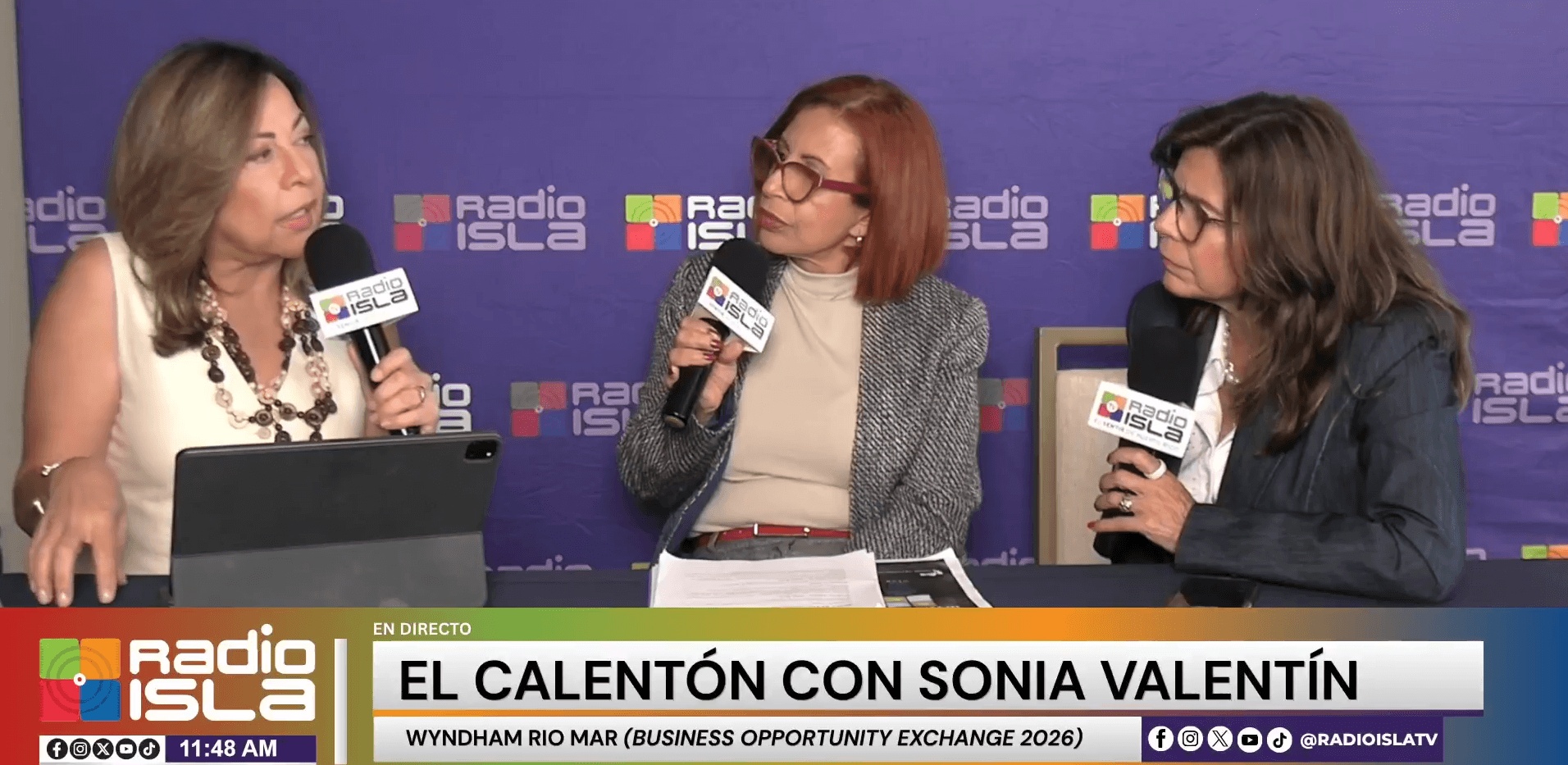 Monika Mantilla, seated at right with a microphone, joins a Radio Isla conversation during Business Opportunity Exchange 2026.