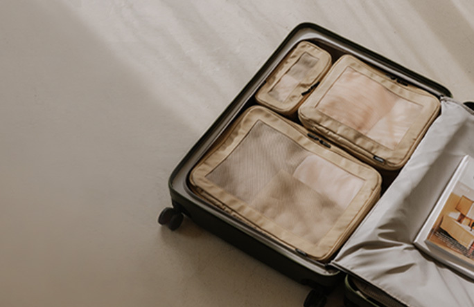 An open Monos suitcase organized with tan compressible packing cubes