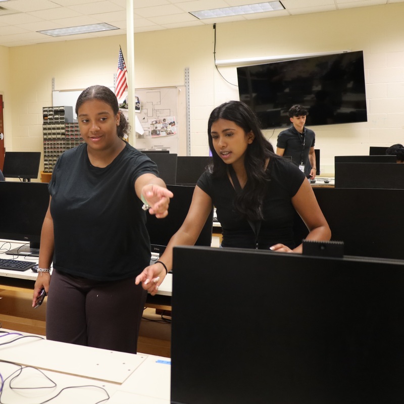 Two Monroe-Woodbury technology interns pointing toward computer equipment