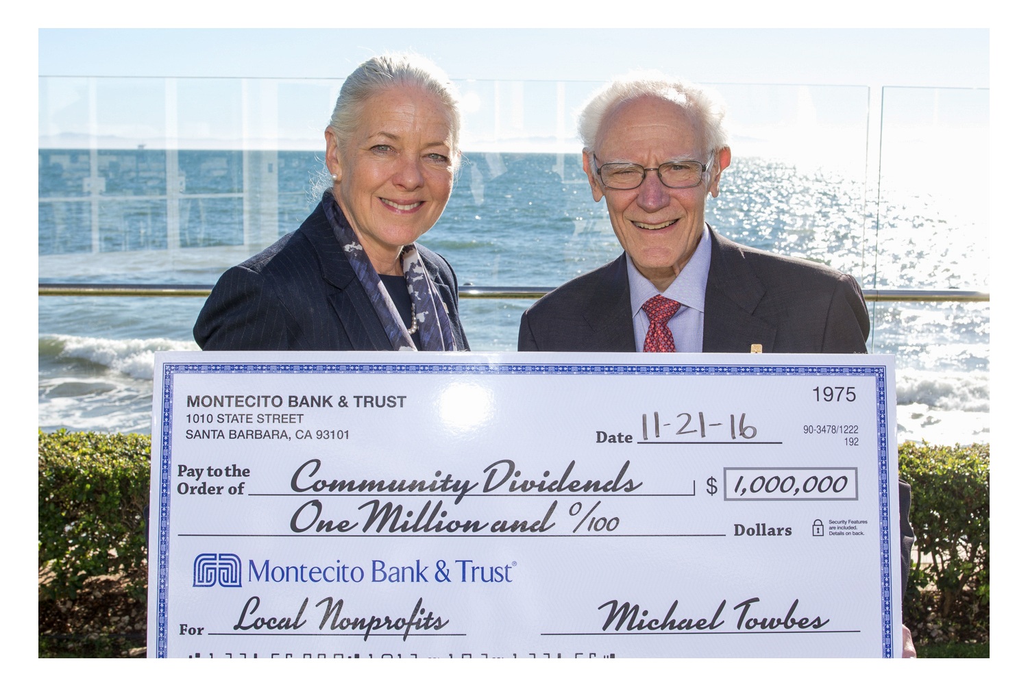 Two bank associates holding a large Community Dividends check for local nonprofits