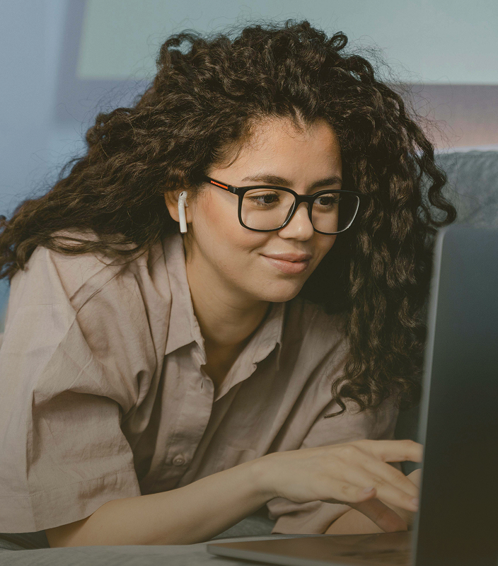 A woman wearing earbuds at a laptop in Monument’s promotional photography