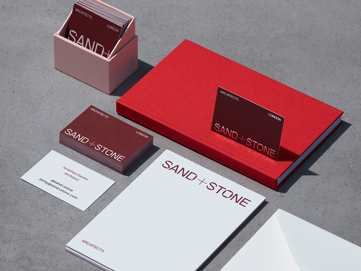 Coordinated burgundy business cards, white stationery and a red notebook in a MOO product photograph
