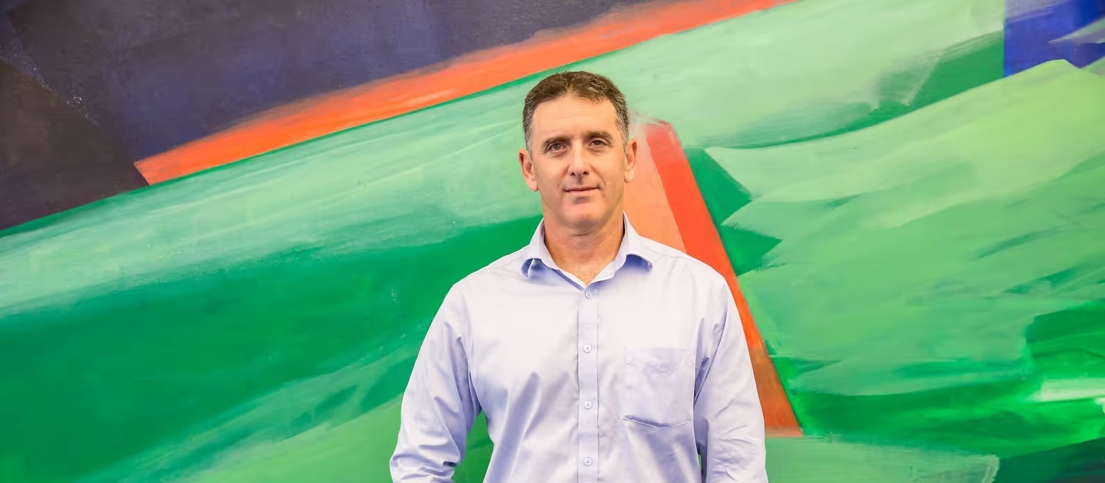 Moovit co-founder Nir Erez standing in front of an abstract green and orange painting
