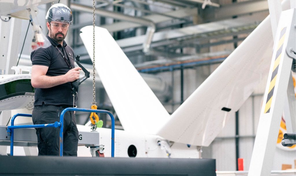 An engineer working beside a Vertical Aerospace VX4 aircraft in an assembly facility