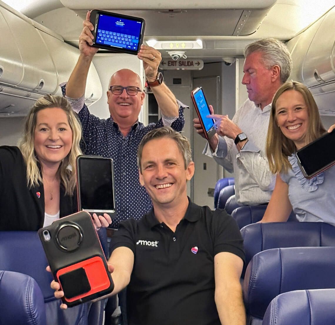 A group inside a Southwest aircraft showing tablets fitted with MOST payment hardware