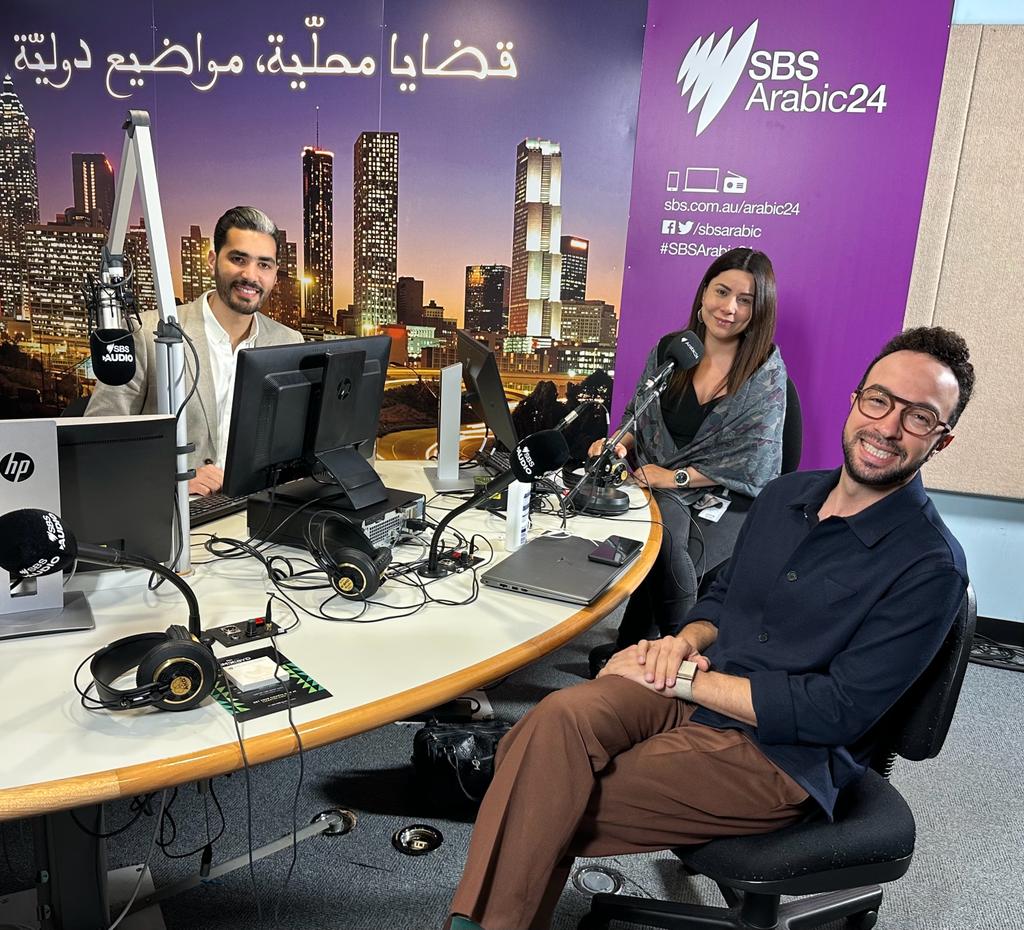 Mostafa Elbermawy, seated at right, with broadcasters Petra Taok Al Hindy and Fares Hassan in the SBS Arabic24 studio