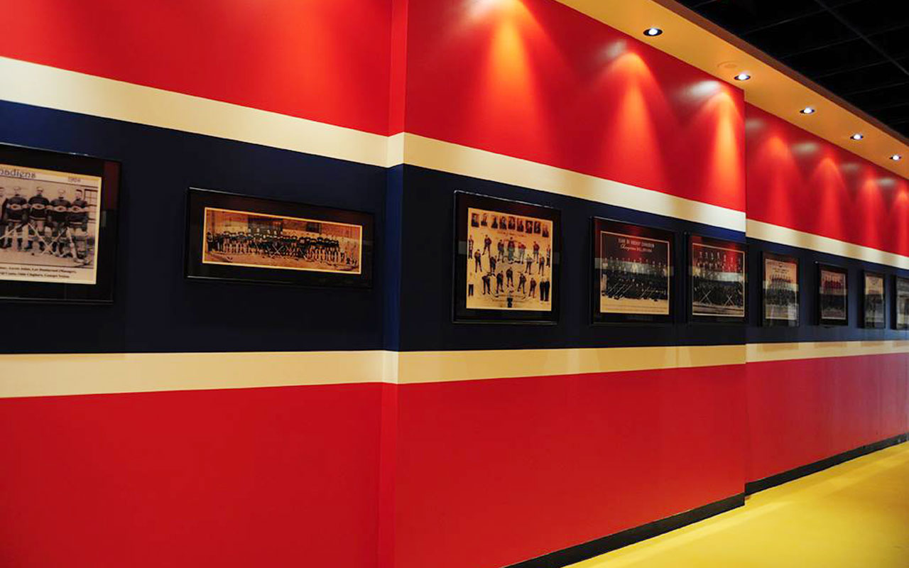 Red and navy Montreal Forum corridor lined with framed historical team photographs.