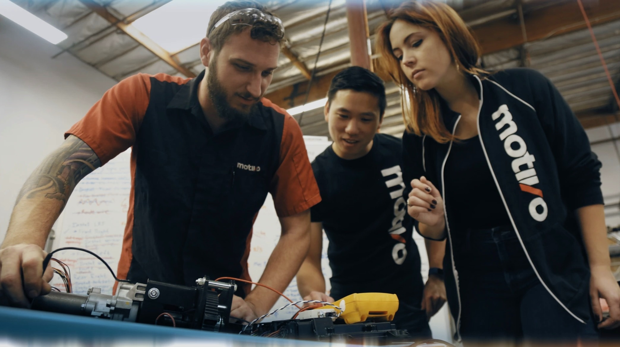 Motivo engineers collaborating around a workbench in the company's facility