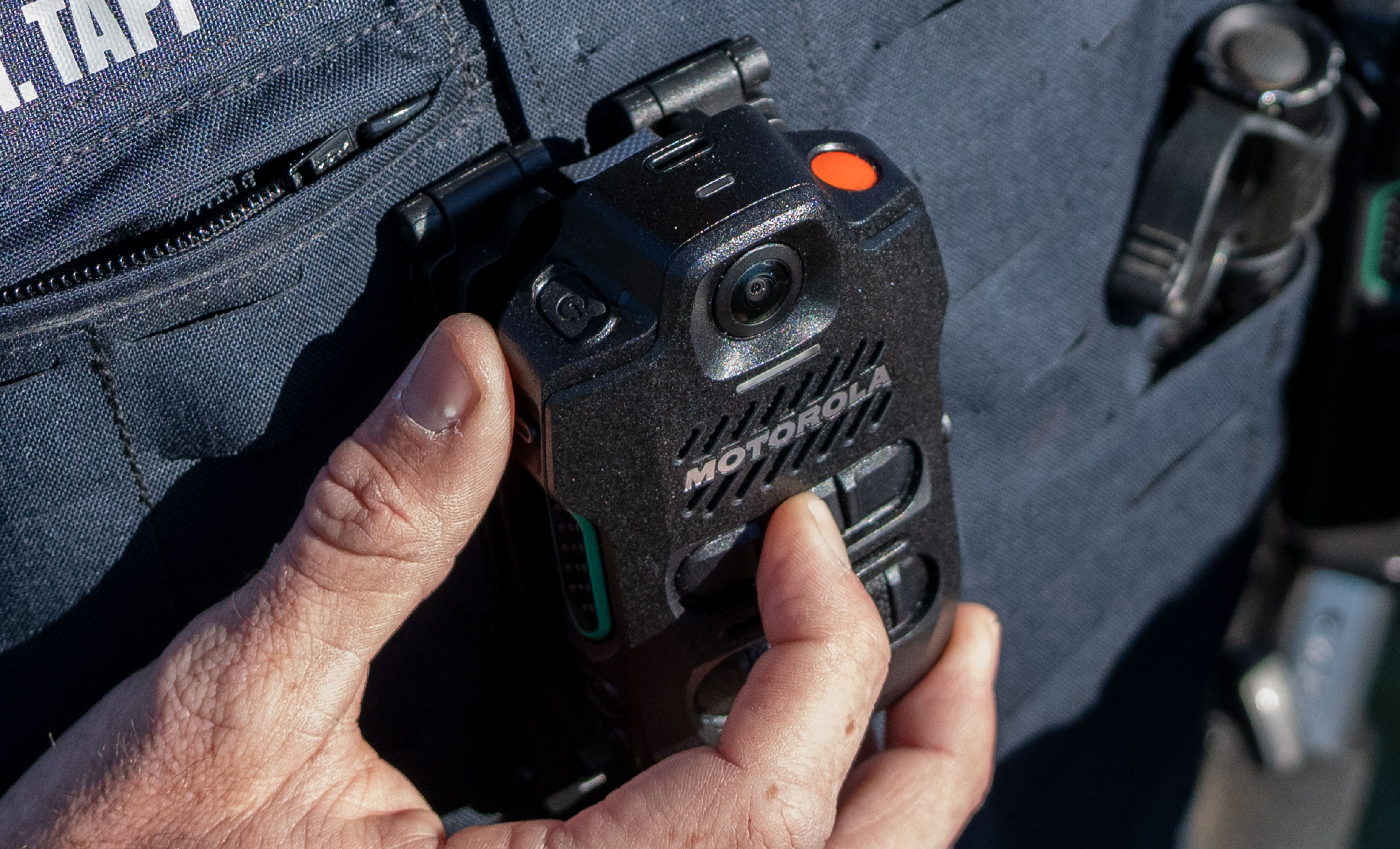 Close-up of an officer holding an SVX speaker microphone with an integrated camera