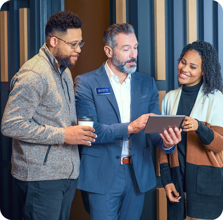 Three people look at a tablet during a consultation in Motto Mortgage marketing photography