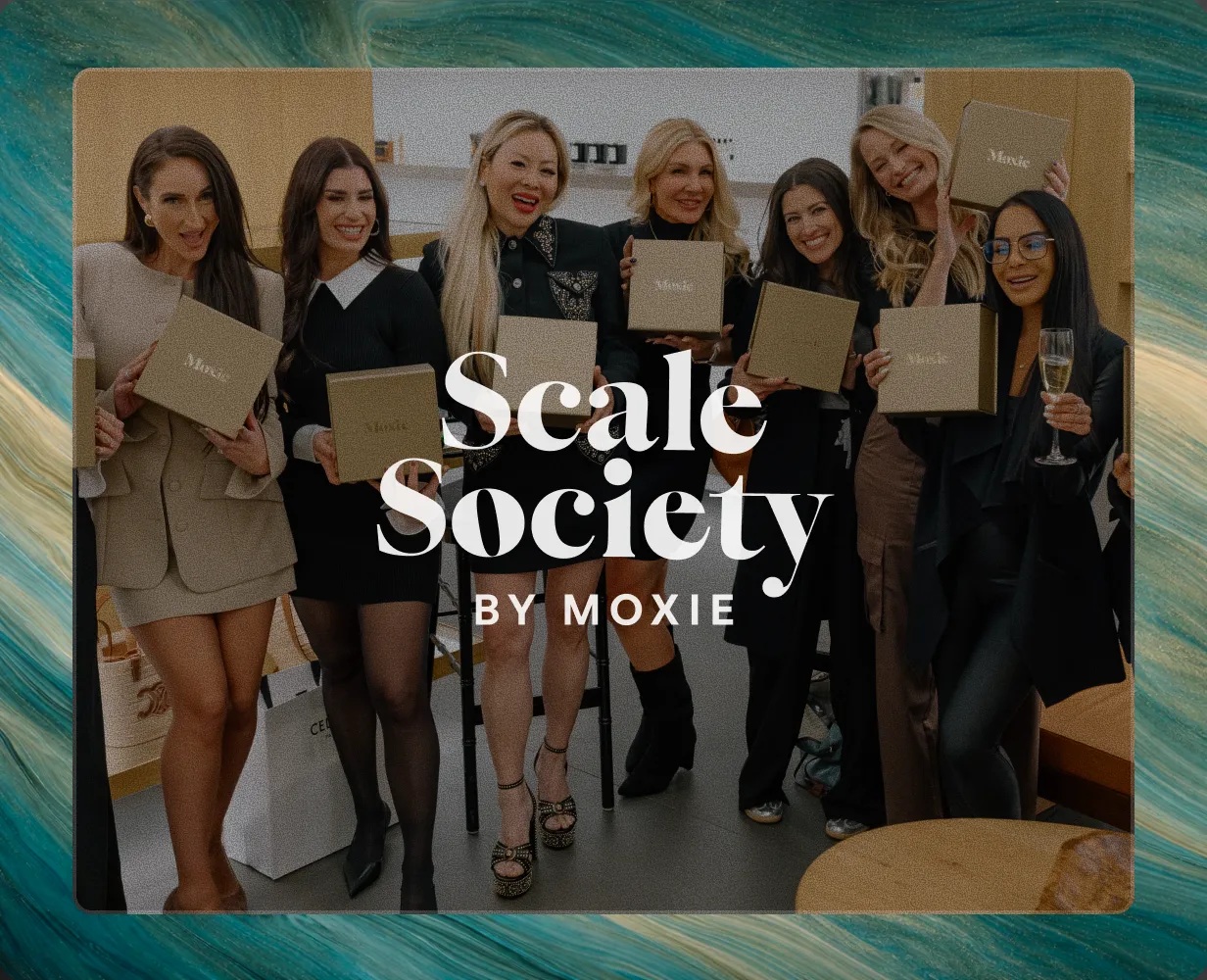 Seven women at a Moxie gathering holding branded gift boxes