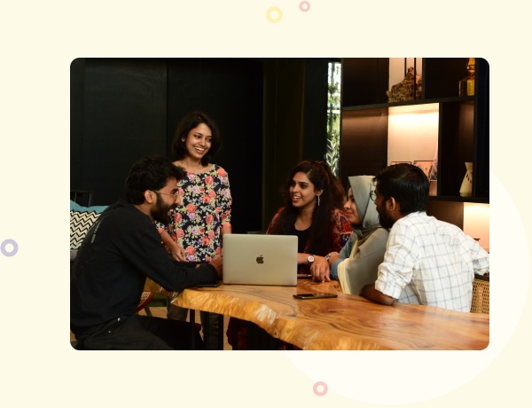 Four Mozilor team members gathered around a laptop at a wooden table