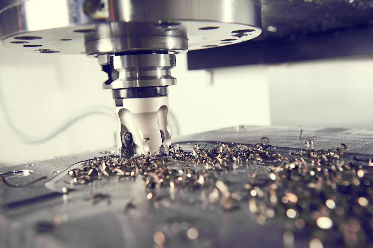 A milling cutter removing metal, with curled chips scattered across the workpiece