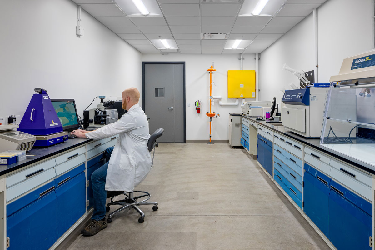 A researcher works at a bench among shared laboratory equipment at the VanCamp Incubator