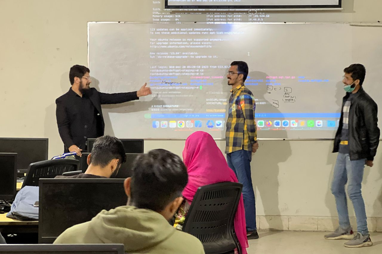 Muhammad Akif Malhi gestures beside a projected computer terminal during a National Textile University workshop.