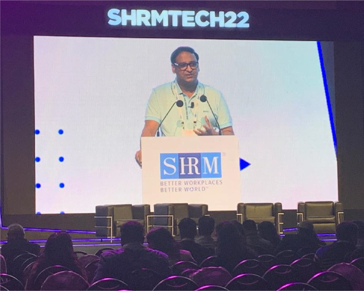 Mukul Jain speaking from a lectern at SHRMTech22 in Hyderabad
