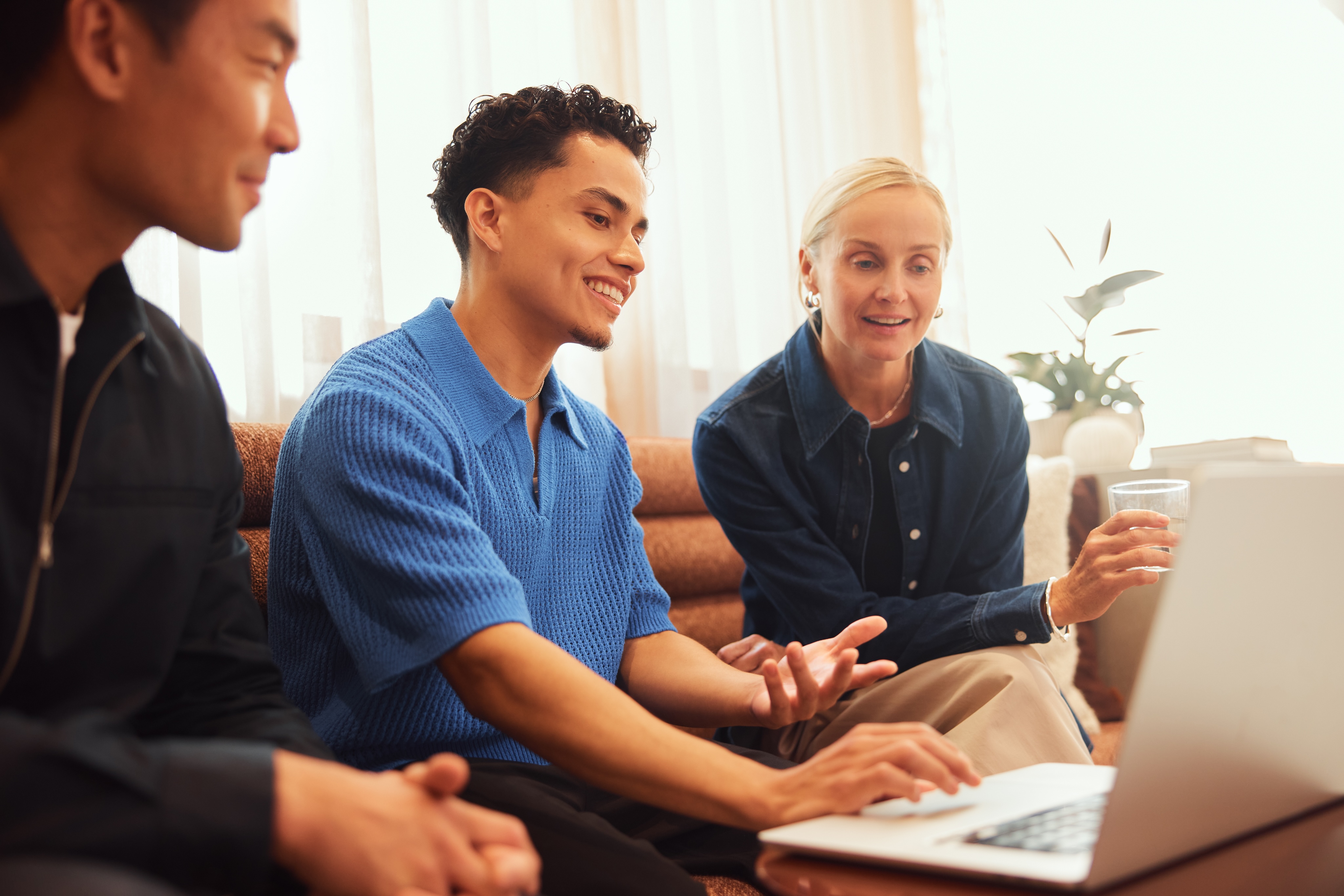 Three people working together around a laptop in Multiverse promotional photography