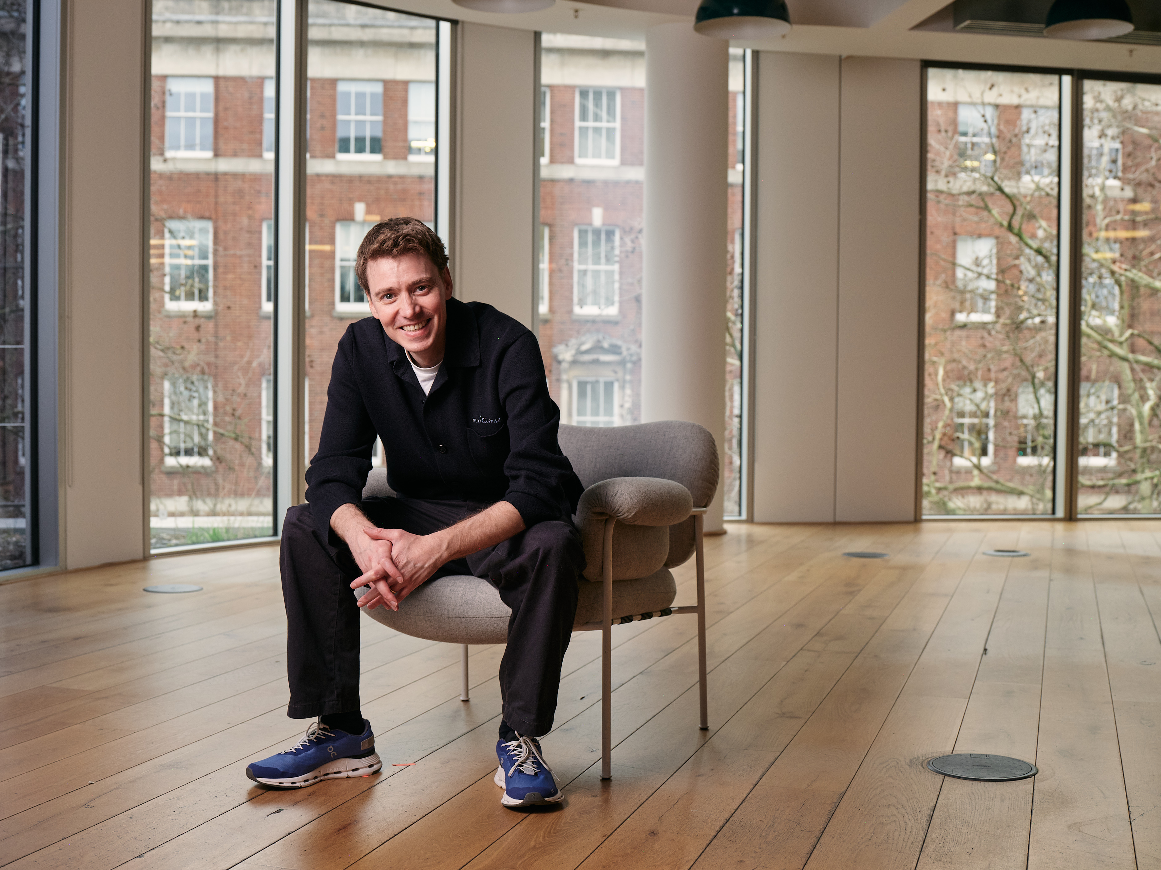 Euan Blair seated beside tall office windows