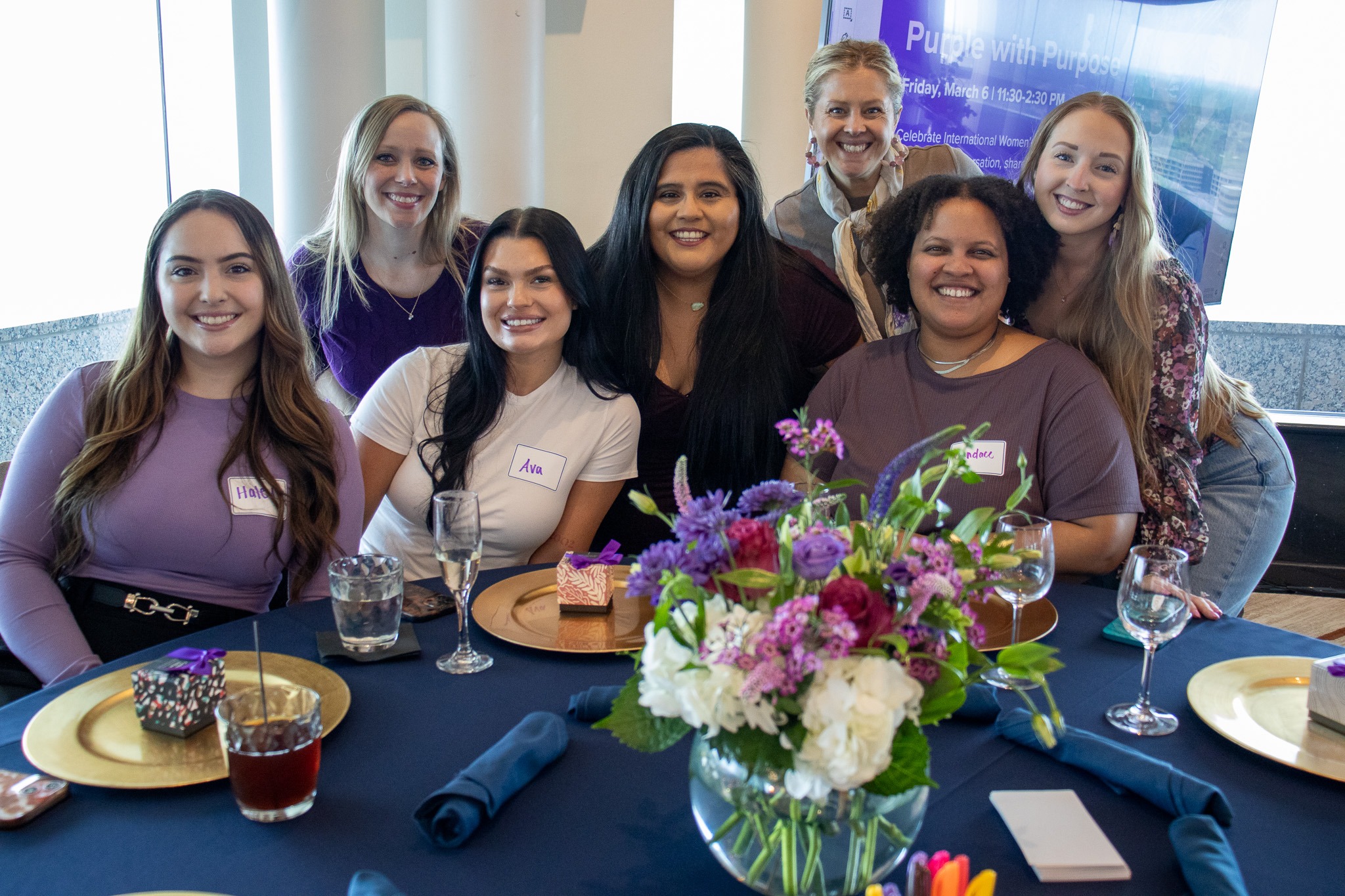 Seven people gathered around a flower-filled table in a photograph published by Multiview