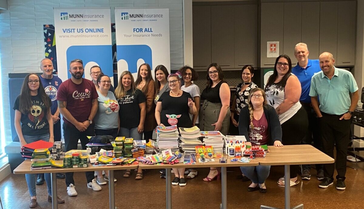 Munn Insurance employees standing behind a table of donated school supplies