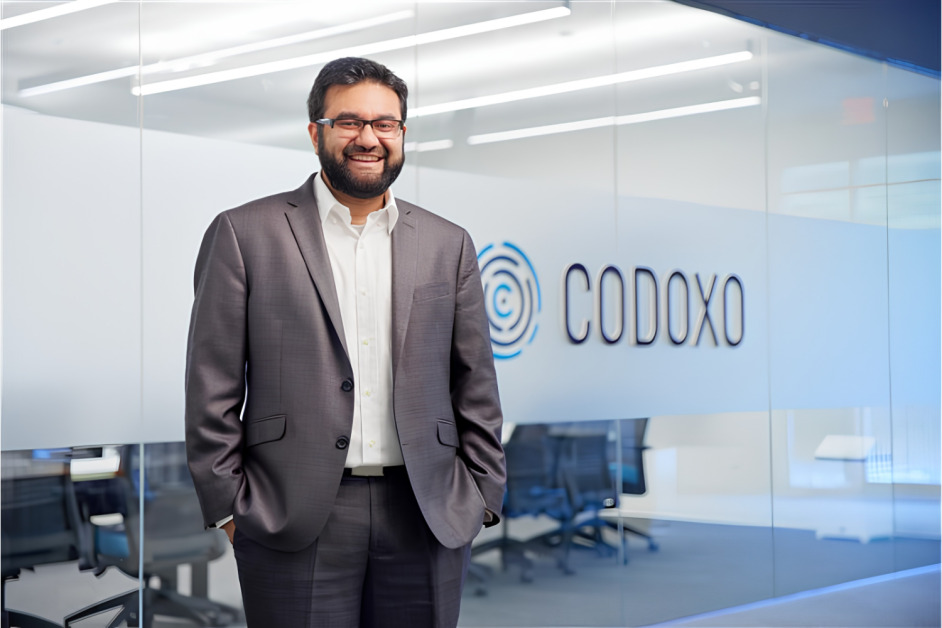 Musheer Ahmed standing in the Codoxo office beside the company name