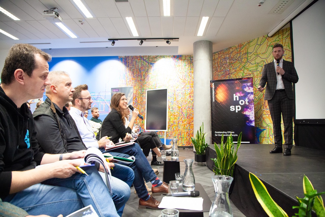 A startup presentation at Hotspot, with audience members holding notebooks and microphones