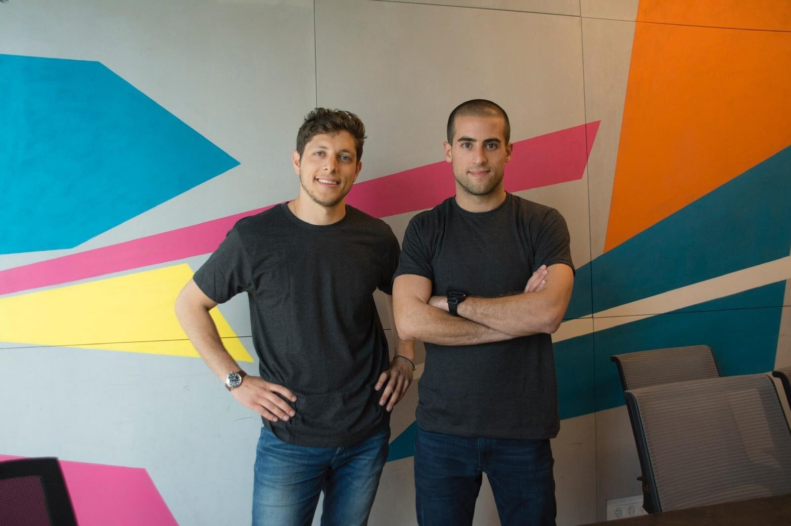 OpenWeb co-founders Roee Goldberg on the left and Nadav Shoval on the right, standing in front of a colorful wall