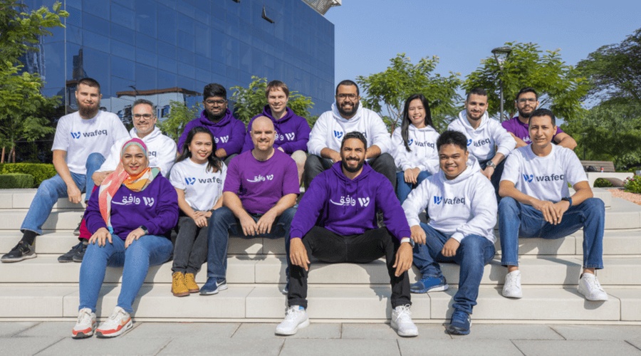Nadim Alameddine seated with the Wafeq team outdoors, wearing purple and white company shirts