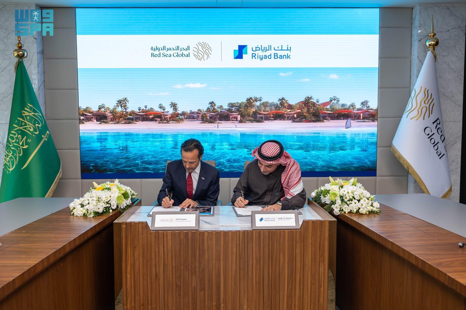 John Pagano and Nadir Al-Koraya sign documents at a Red Sea Global and Riyad Bank table