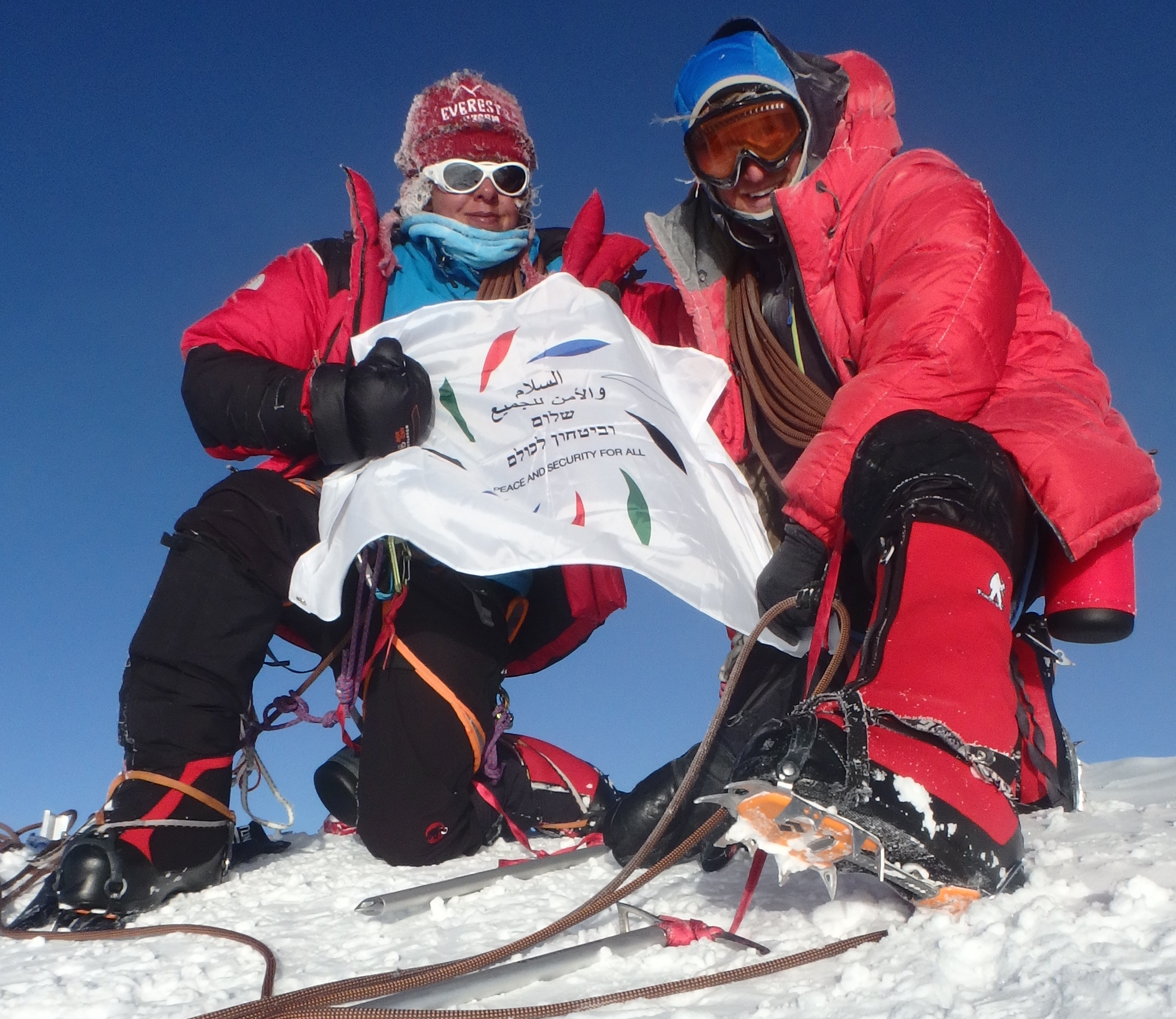 Naira Musallam and Tim Lawton holding their multilingual flag on Denali’s summit
