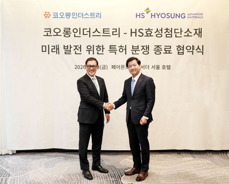Heo Sung of Kolon Industries, left, shakes hands with Nakyang Seong after the patent-dispute agreement in Seoul.