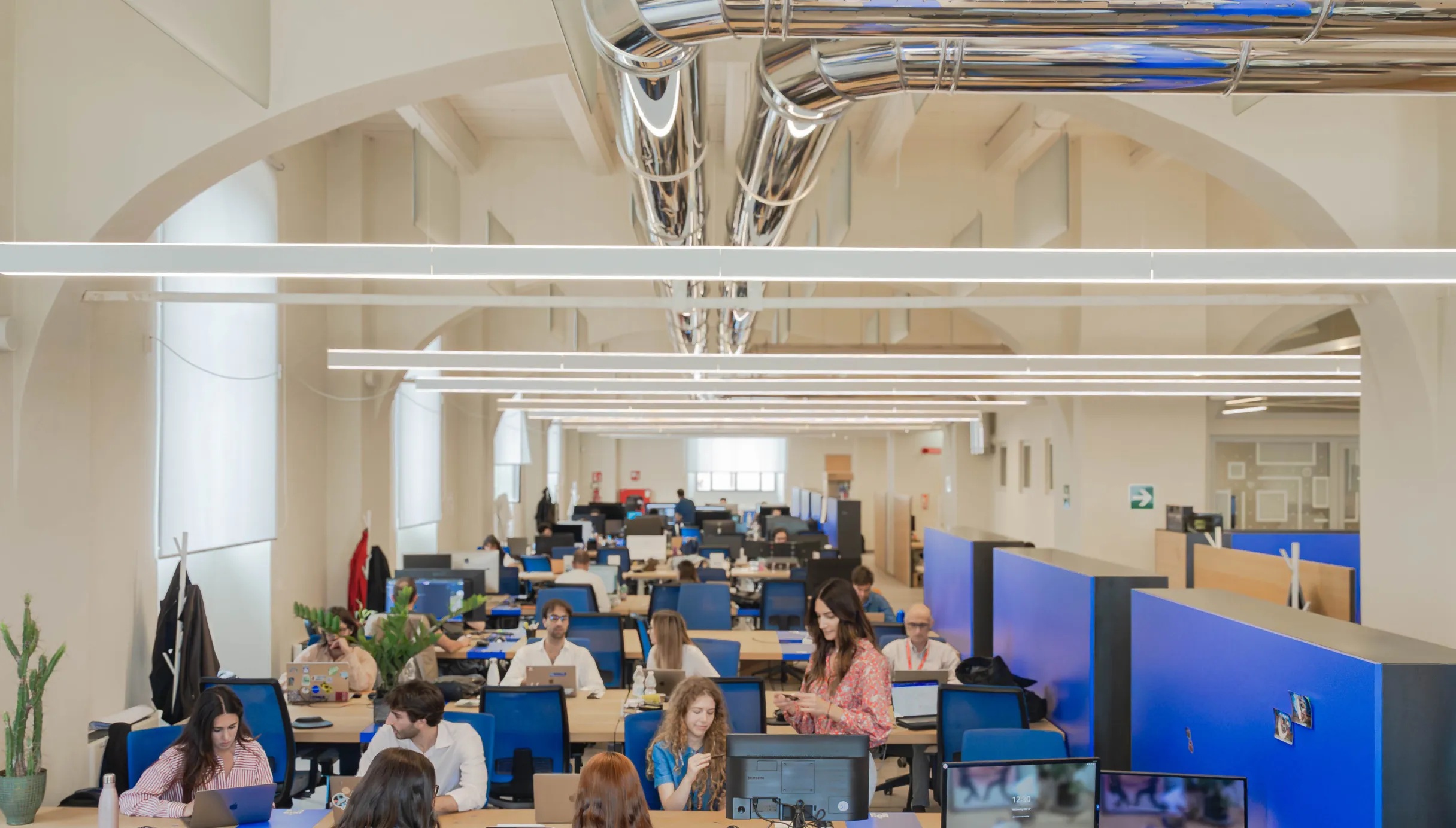 People working beneath vaulted ceilings in Nana Bianca’s Florence coworking space