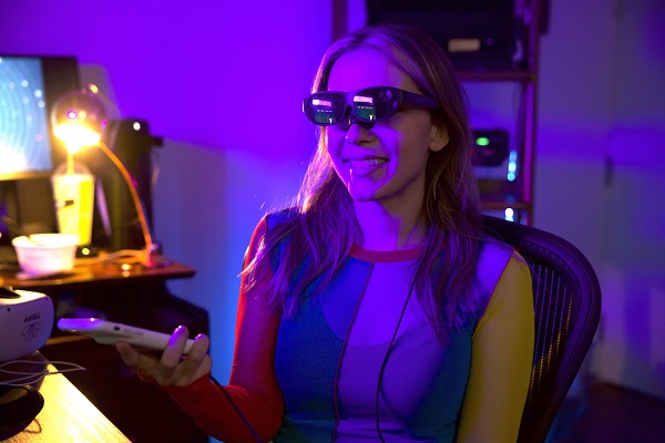 Nanea Reeves wearing smart glasses in a colorful technology workspace