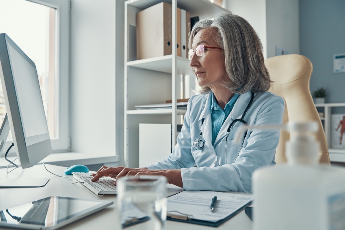 A clinician working at a desktop computer in an office